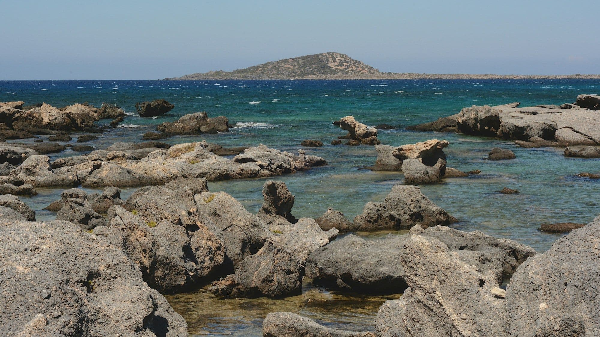 Rocky Cretan coastline and blue Aegean Sea beneath a clear sky